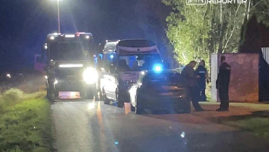 Grupa funkcjonariuszy policji prowadzi czynności na drodze, obok zaparkowanych pojazdów w nocy.