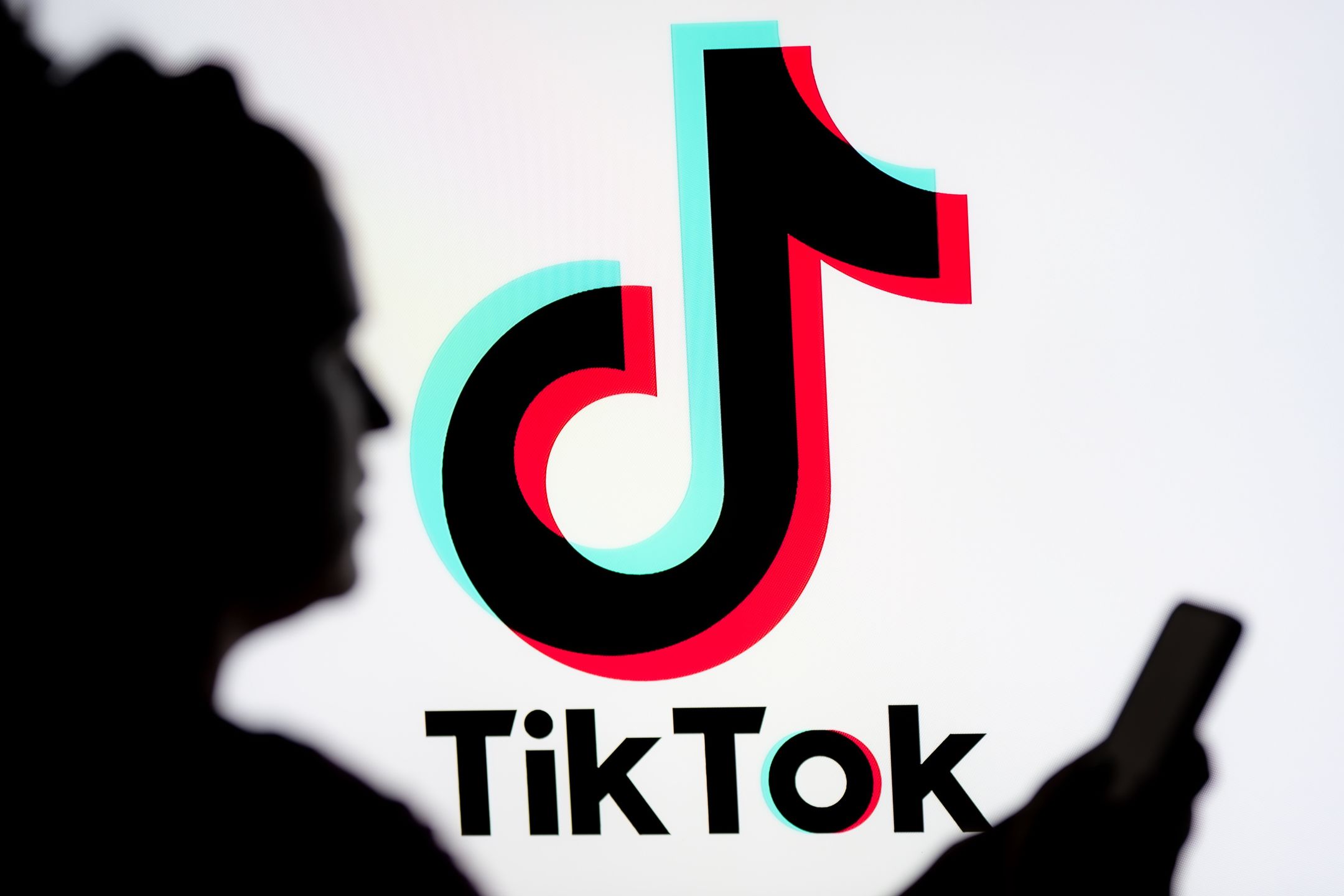 POLAND - 2025/03/07: In this photo illustration, a woman seen looking at a smartphone with a TikTok logo displayed in the background. (Photo Illustration by Mateusz Slodkowski/SOPA Images/LightRocket via Getty Images)