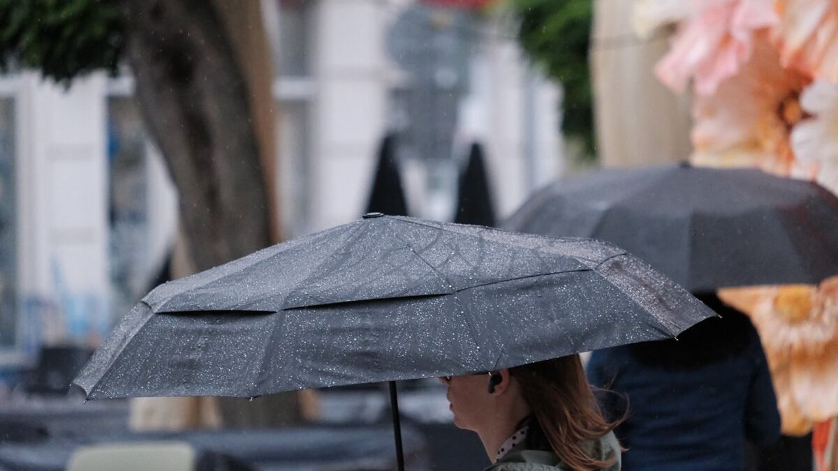 Kobieta pod parasolem w trakcie opadów deszczu