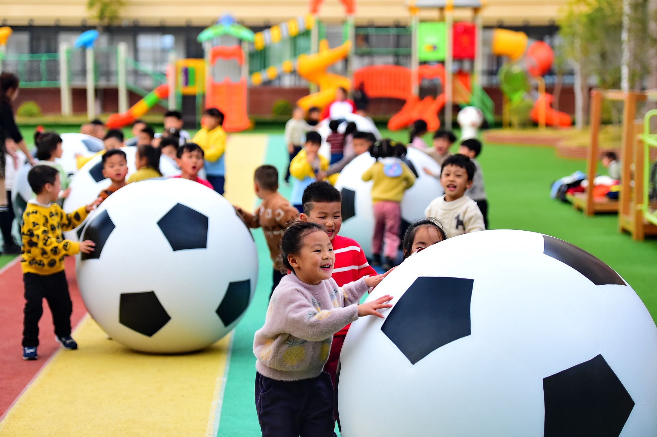 HUICHANG, CHINA - DECEMBER 29: Children play big footballs at a kindergarden on December 29, 2020 in Huichang County, Jiangxi Province of China. (Photo by Zhu Haipeng/VCG via Getty Images)