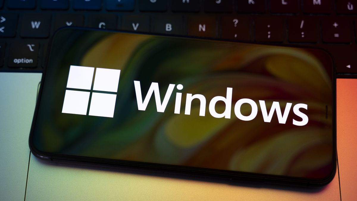 The Windows logo appears on the screen of a smartphone placed on a computer keyboard illuminated by orange and green light. Microsoft releases a major update to Windows 11 (25H2), and Windows 10 support ends permanently on October 14. In Creteil, France, on October 9, 2025. (Photo by Samuel Boivin/NurPhoto via Getty Images)