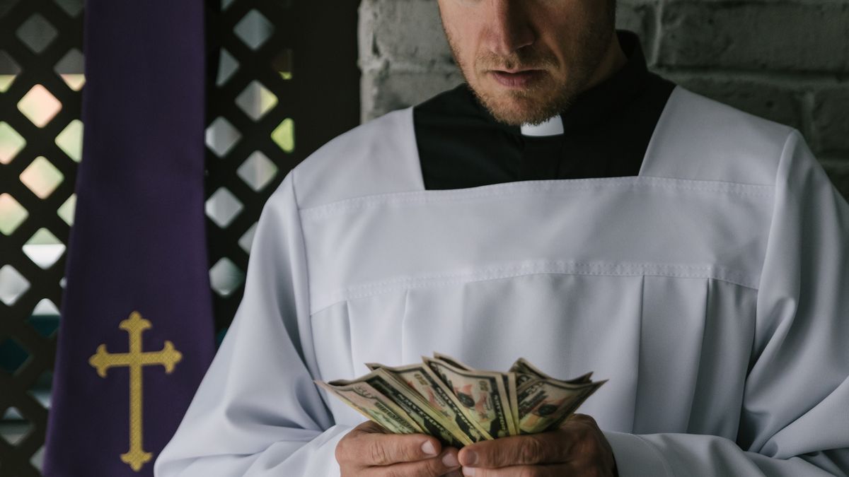 Catholic priest counting money in his handCatholic priest counting money in his hand. Church and moneydjedzura