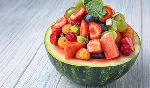 Delicious fruit salad in watermelon bowl on light wooden table