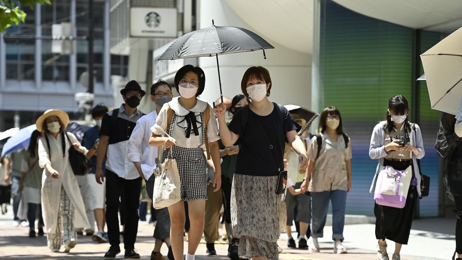 TOKYO, JAPAN - JULY 31: People walking in the street wear a protective mask as a precaution against the coronavirus (Covid-19) on July 31, 2022 in Tokyo, Japan. Japanese capital is swept by a heat wave whose temperature reaches 38 degrees Celsius and more in certain districts and suburbs close to the city. While Japan is facing a new wave of Covid-19 contamination in recent days, the capital is recording contamination records this week amounting to 40,000 people in just one day, a number never recorded in such a short time in Japan. Following the growing number of infected people in Tokyo, several major events related to the summer season have been canceled or restricted in order to contain the spread of the new omicron strain of Covid-19. (Photo by David Mareuil/Anadolu Agency via Getty Images)