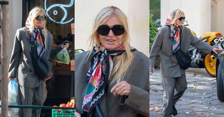 Monika Olejnik w garniturze i kolorowej chuście na głowie człapie na zakupy do warzywniaka