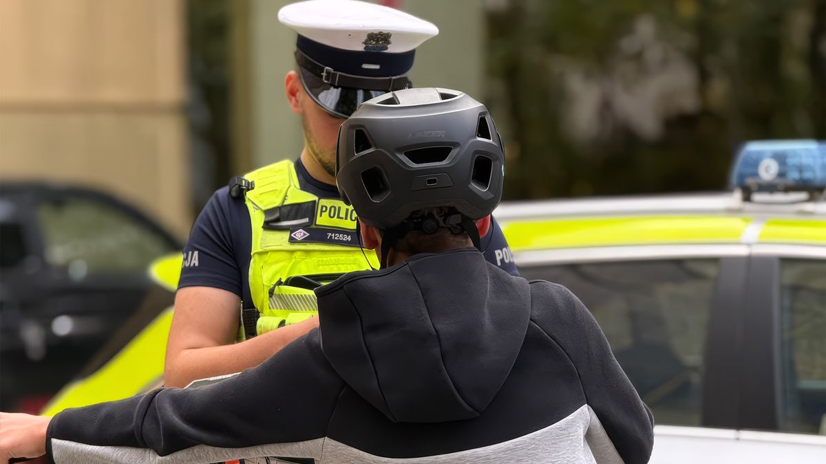 Policjant ruchu drogowego rozmawia z młodym rowerzystą na ulicy
