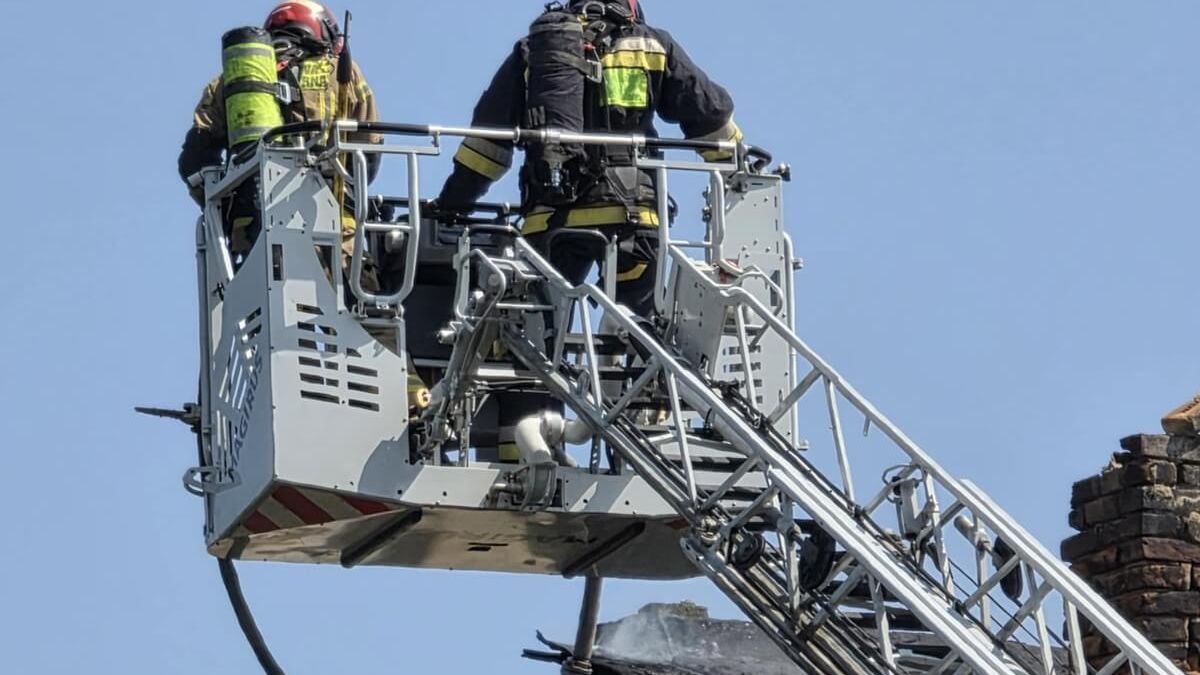 Strażacy gaszący pożar z kosza drabiny hydraulicznej