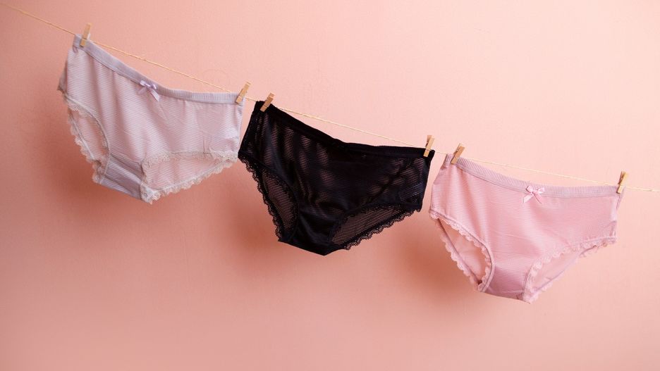 colorful clean women&#39;s panties hang on a rope. on a pink isolated background