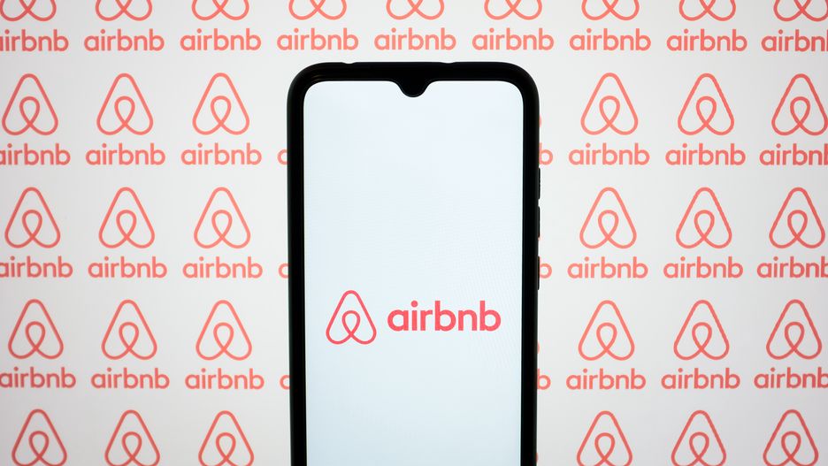 The Airbnb logos are being displayed on a smartphone screen and on a computer screen in Athens, Greece, on May 10, 2024. (Photo by Nikolas Kokovlis/NurPhoto via Getty Images)