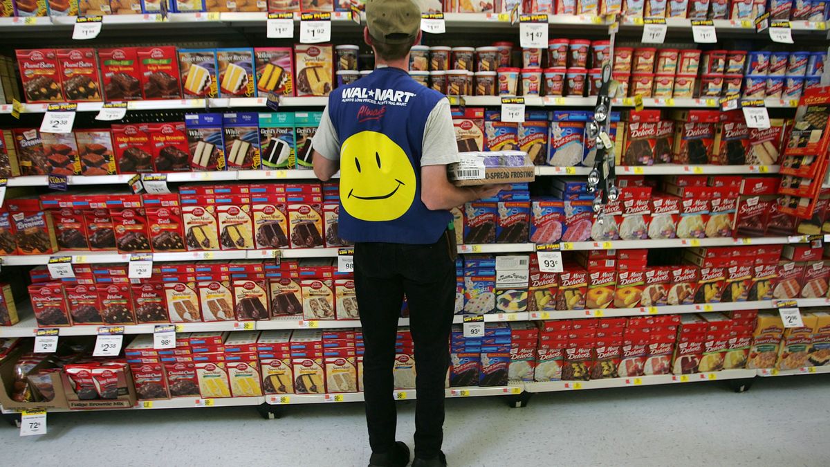 Wal-Mart Dominates U.S. Retail EconomyTROY, OH - MAY 11:  An employee restocks a shelf in the grocery section of a Wal-Mart Supercenter May 11, 2005 in Troy, Ohio. Wal-Mart, America's largest retailer and the largest company in the world based on revenue, has evolved into a giant economic force for the U.S. economy. With growth, the company continues to weather criticism of low wages, anti-union policies as well as accusations that it has homogenized America's retail economy and driven traditional stores and shops out of business.  (Photo by Chris Hondros/Getty Images)Chris HondrosEOS1DMkII-234398 yellow smiling face logo rear back commerce com