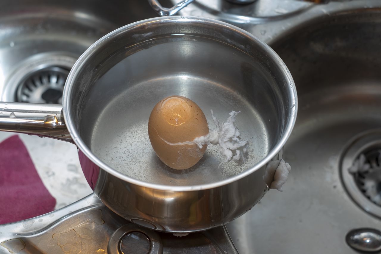 What should be done to prevent an eggshell from cracking during boiling?