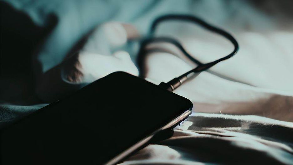 Telefon ładowany w nocy na pościeli