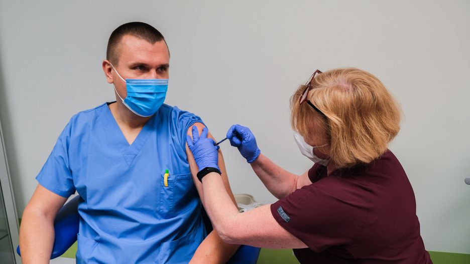 KRAKOW, POLAND - DECEMBER 27: Tomasz Drygalski, a doctor from the Intensive Care Unit  is given the first jab of Pfizer BioNTech Covid-19 vaccine by the nurse, Renata Krawczyk at Krakow University Hospital on December 27, 2020 in Krakow, Poland. On Friday , December 25, the first 10,000 jabs of Pfizer BioNTech Covid-19 vaccine were delivered to Poland. Today, 72 hospitals across the country start the first stage (stage 0) out of 4, where health workers fighting the coronavirus will be vaccinated in the following days. The European Medicines Agency approved the Pfizer/BioNTech covid-19 vaccine on Monday, paving the way for a Dec. 27 rollout among EU countries.  (Photo by Omar Marques/Getty Images)
