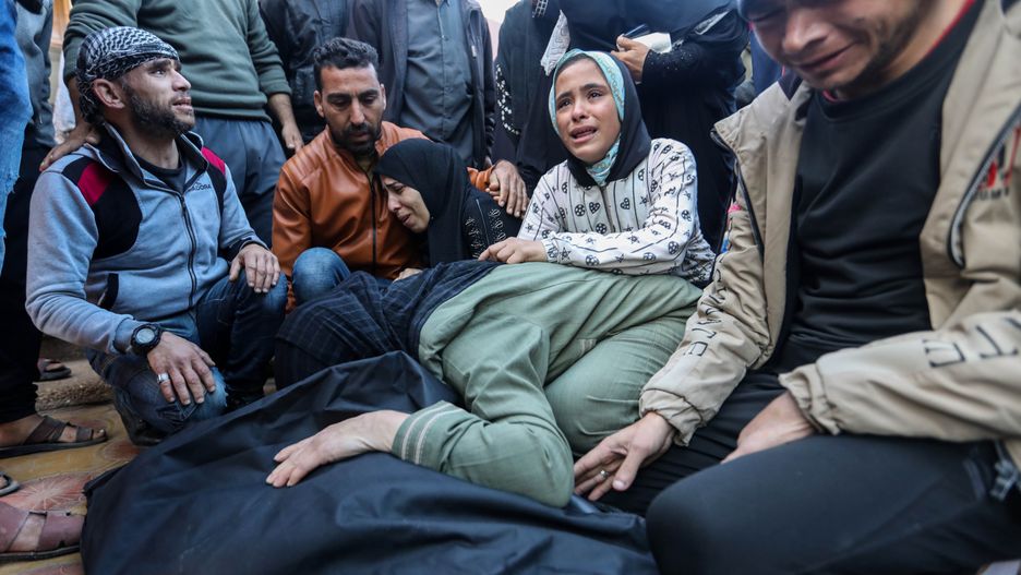 KHAN YUNIS, GAZA - DECEMBER 18: People mourn as they collect the bodies of Palestinians killed in an airstrike on December 18, 2023 in Khan Yunis, Gaza. The United Kingdom, France and Germany are the latest countries to call on Israel to reach a "sustainable truce" after more than two months of war in Gaza, which was sparked by the Oct. 7 attacks by Hamas that left 1,200 dead and around 240 taken hostage. In Israel's retaliatory air and ground offensive, nearly 20,000 Palestinians have been killed, according to Gaza health officials. The Israeli prime minister has resisted calls for a ceasefire, saying last week that "military pressure is necessary both for the return of the hostages and for victory." (Photo by Ahmad Hasaballah/Getty Images)
