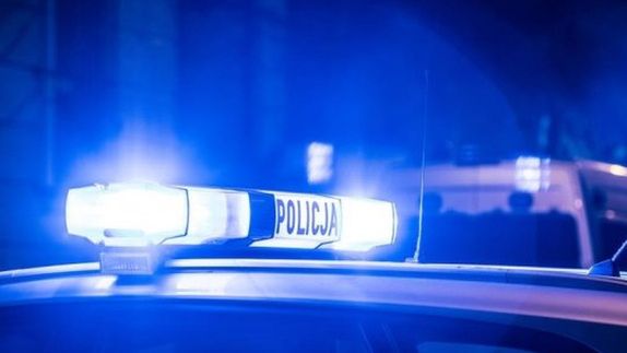 Niebieskie światła policyjne migają na dachu radiowozu w nocy.