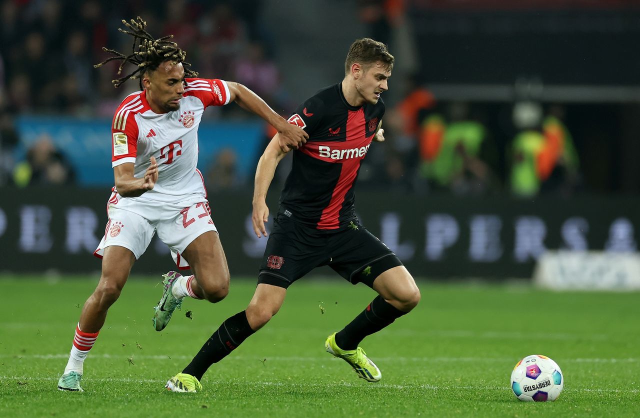 LEVERKUSEN, GERMANY - FEBRUARY 10: Sacha Boey of Muenchen challenges Josip Stanisic of Bayer Leverkusen during the Bundesliga match between Bayer 04 Leverkusen and FC Bayern München at BayArena on February 10, 2024 in Leverkusen, Germany. (Photo by Lars Baron/Getty Images)