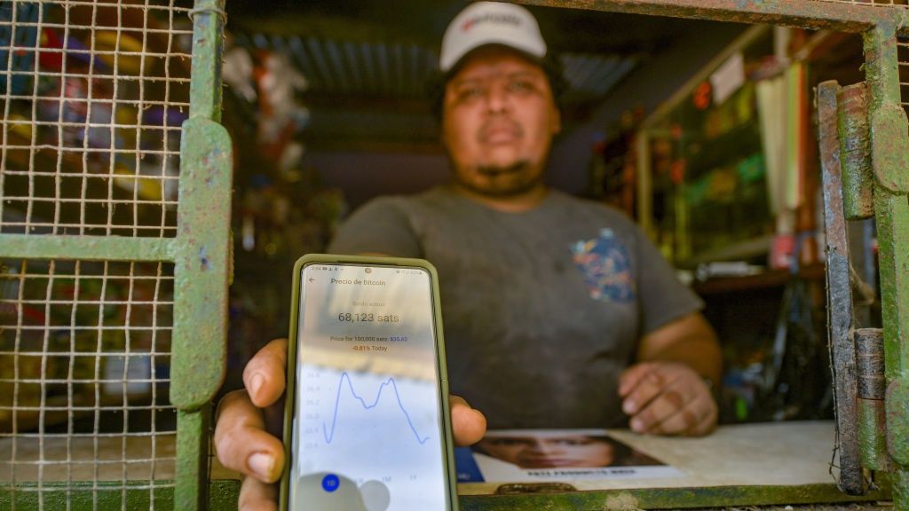 Mieszkaniec Salwadoru pokazuje telefon z wykresem bitcoina