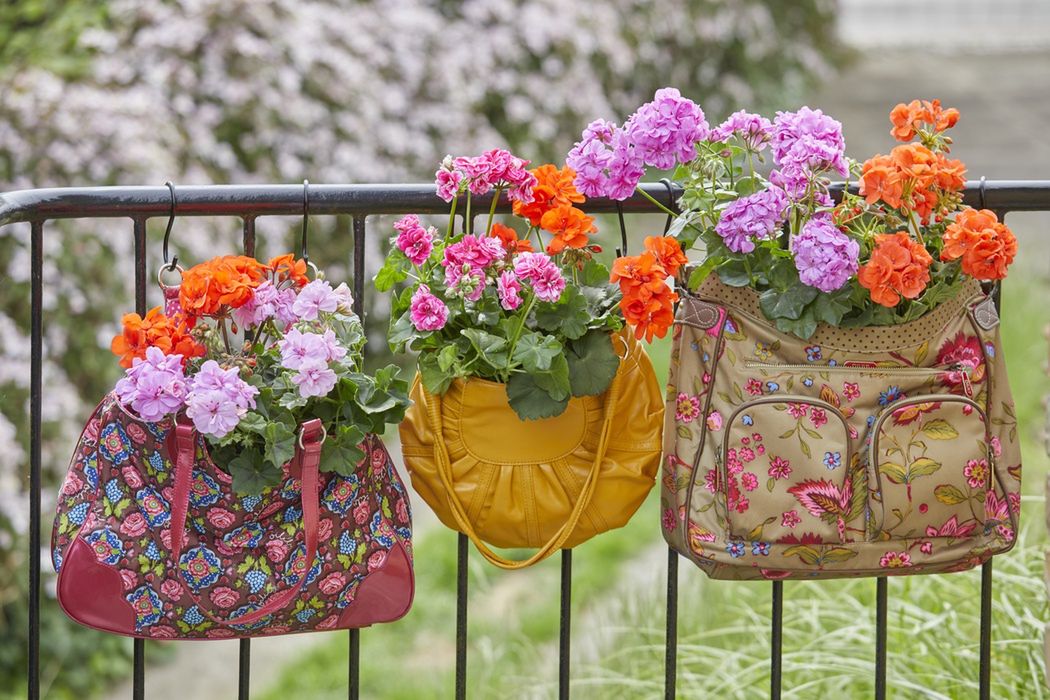 Kolorowe pelargonie we wzorzystych torebkach vintage zawieszonych na metalowych balustradach. Alternatywa dla tradycyjnych doniczek