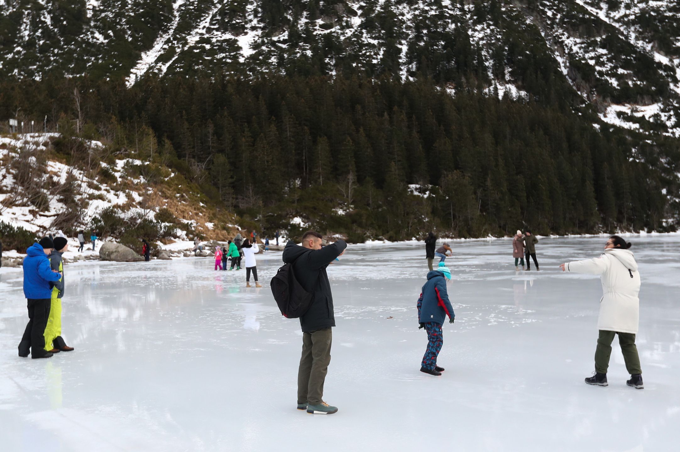Tatry, Morskie Oko, 26.12.2022. Turyści na tafli lodu na jeziorze Morskie Oko w Tatrach, 26 bm. Tatrzański Park Narodowy ostrzega przed wchodzeniem na zamarznięte górskie jeziora � z powodu panujących w ciągu dnia dodatnich temperatur lód jest bardzo cienki i grozi załamaniem. (jm) PAP/Grzegorz Momot