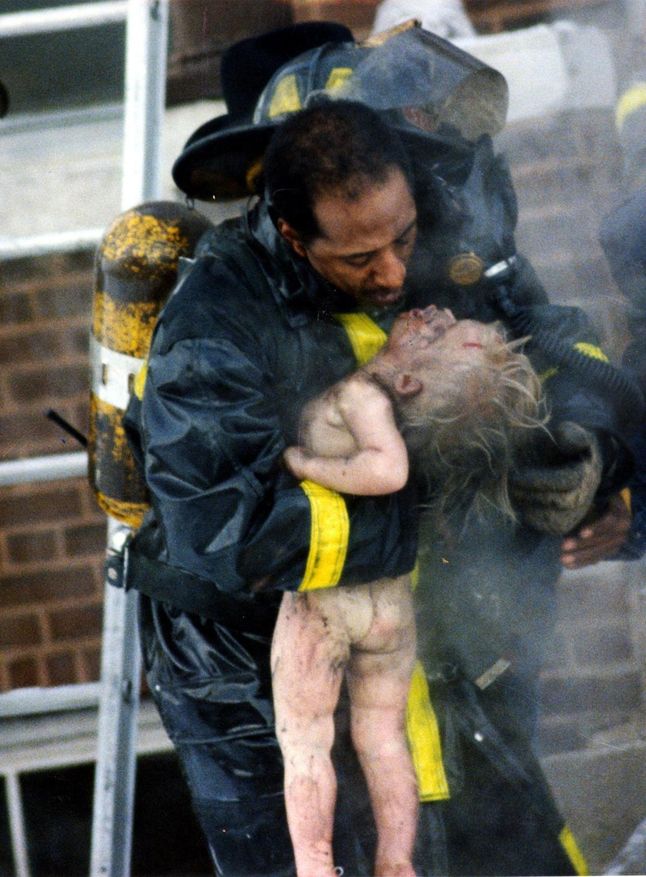 Strażak reanimuje dziecko wyciągnięte z płonącego budynku metodą usta-usta.