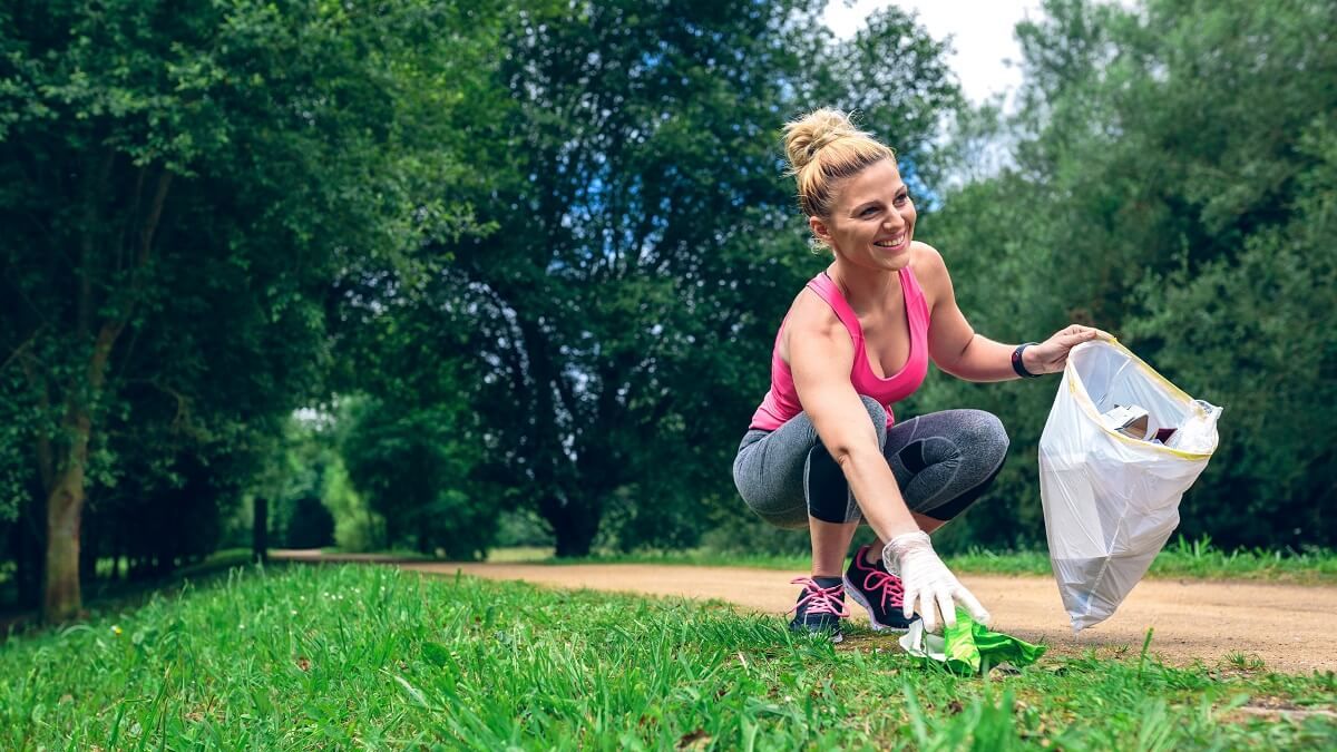 plogging - kobieta biegając zbiera śmieci