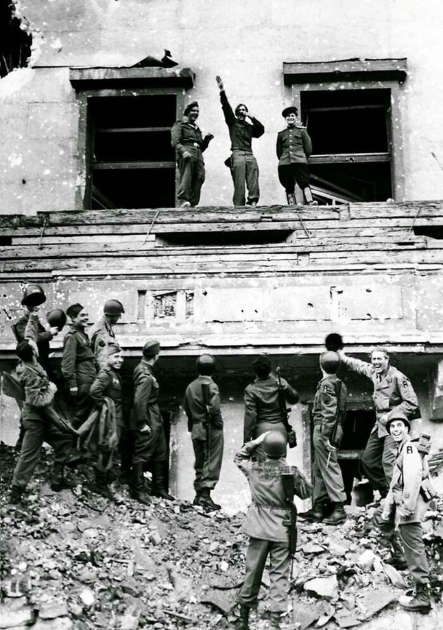 Alianci naśmiewający się z Hitlera na balkonie zniszczonej kancelarii III Rzeszy (1945).