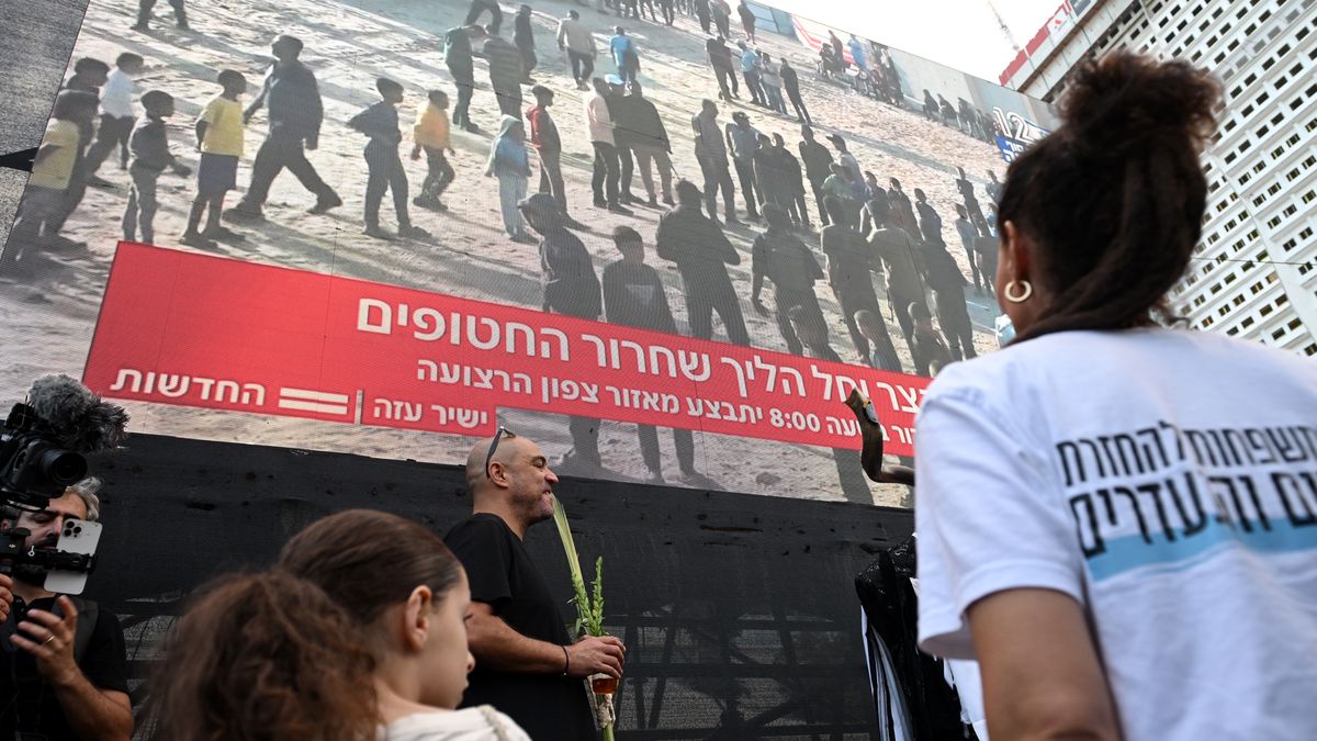 TEL AVIV, ISRAEL - OCTOBER 13: People watch a large screen broadcasting a live feed of Gaza, as they wait for the start of the hostage release at Hostages Square on October 13, 2025 in Tel Aviv, Israel. The ceasefire deal between Israel and Hamas has brought an end to the two years of war that followed the attacks of Oct. 7, 2023. A condition of the deal was the immediate return of 48 hostages held in Gaza, around 20 of whom were believed to be alive. (Photo by Alexi J. Rosenfeld/Getty Images)