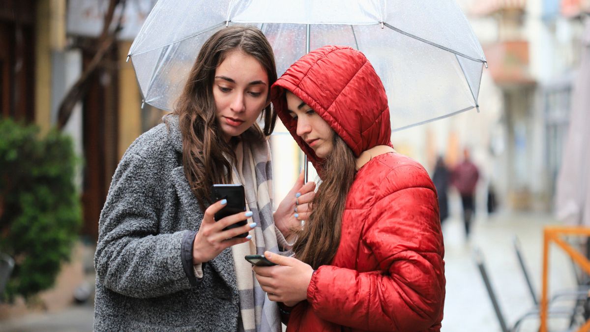 Dwie kobiety patrzą w telefon na ulicy