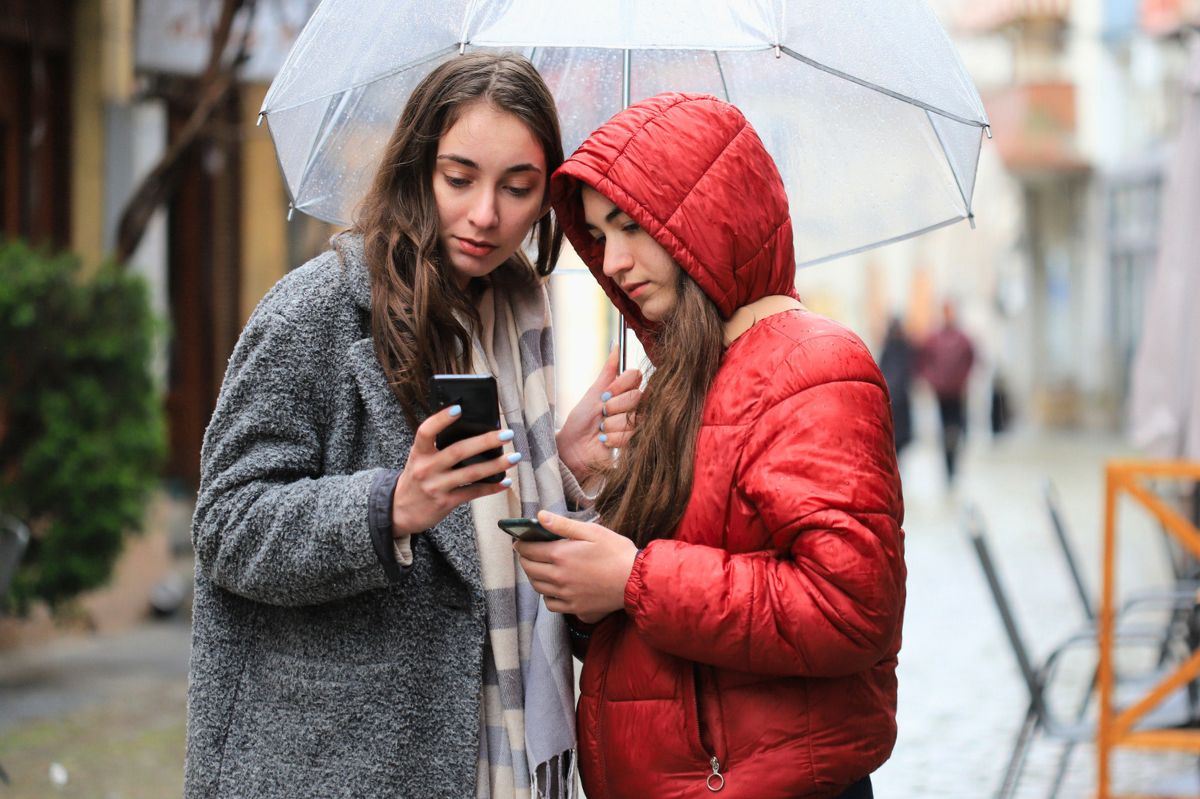 Dwie kobiety patrzą w telefon na ulicy