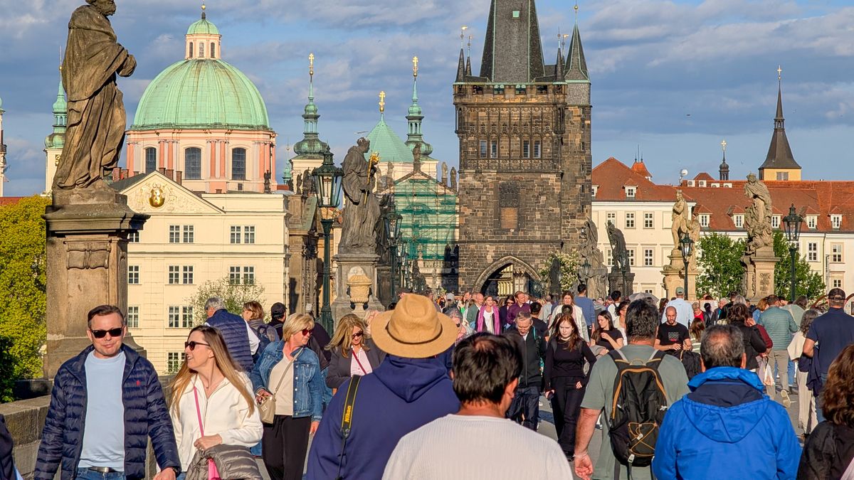 A dense flow of tourists walks along Charles Bridge during golden hour in Prague, Czech Republic, on May 11, 2025. The view toward the Old Town Bridge Tower and surrounding baroque architecture illustrates the popularity of this historic site and the ongoing phenomenon of mass tourism in the Czech capital. (Photo by Michael Nguyen/NurPhoto via Getty Images)