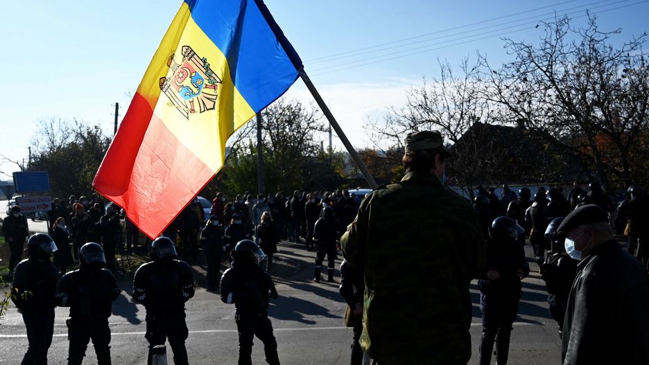 Temporary
A man holds Moldovan national flag as special police officers patrol a street near a polling station during the second round of Moldova's presidential election in the town of Varnita at Moldova - Transnistrian border on November 15, 2020, amid the ongoing Covid-19 pandemic. (Photo by Sergei GAPON / AFP)
SERGEI GAPON
