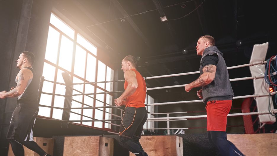 Warming up their muscles. Smilling and focused sportmen in sports clothing running near boxing ring in gymA group of muscular smilling focused sportmen warming up and running near boxing ring before training in gymathlete, sportsman, boxer, fighter, man, warm-up, run, running, training, exercise, preparation, motivation, gym, move, fight, boxing, mma, victory, sport, clothing, athletic, muscular, focused, strong, young, handsome, healthy, tattooed, sports, sporty, muscule, workout, fit, male, body, lifestyle, power, activity, fitness, dressing, person, active, adult, strength, health, energy, indoors, background, masculine, round