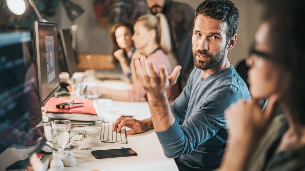 Young male programmer talking to his colleague while working on computers in the office.
Computer programmers communicating while working on desktop PC's in the office.
skynesher