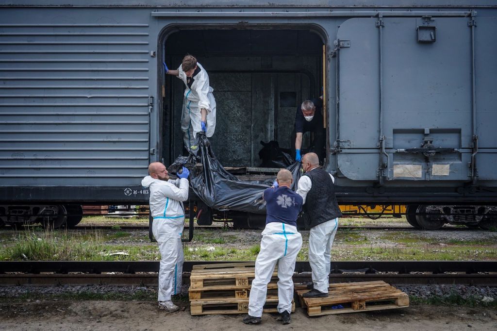 Ukraińscy pracownicy medyczni chowają ciało rosyjskiego żołnierza do wagonu-chłodni pod Kijowem 