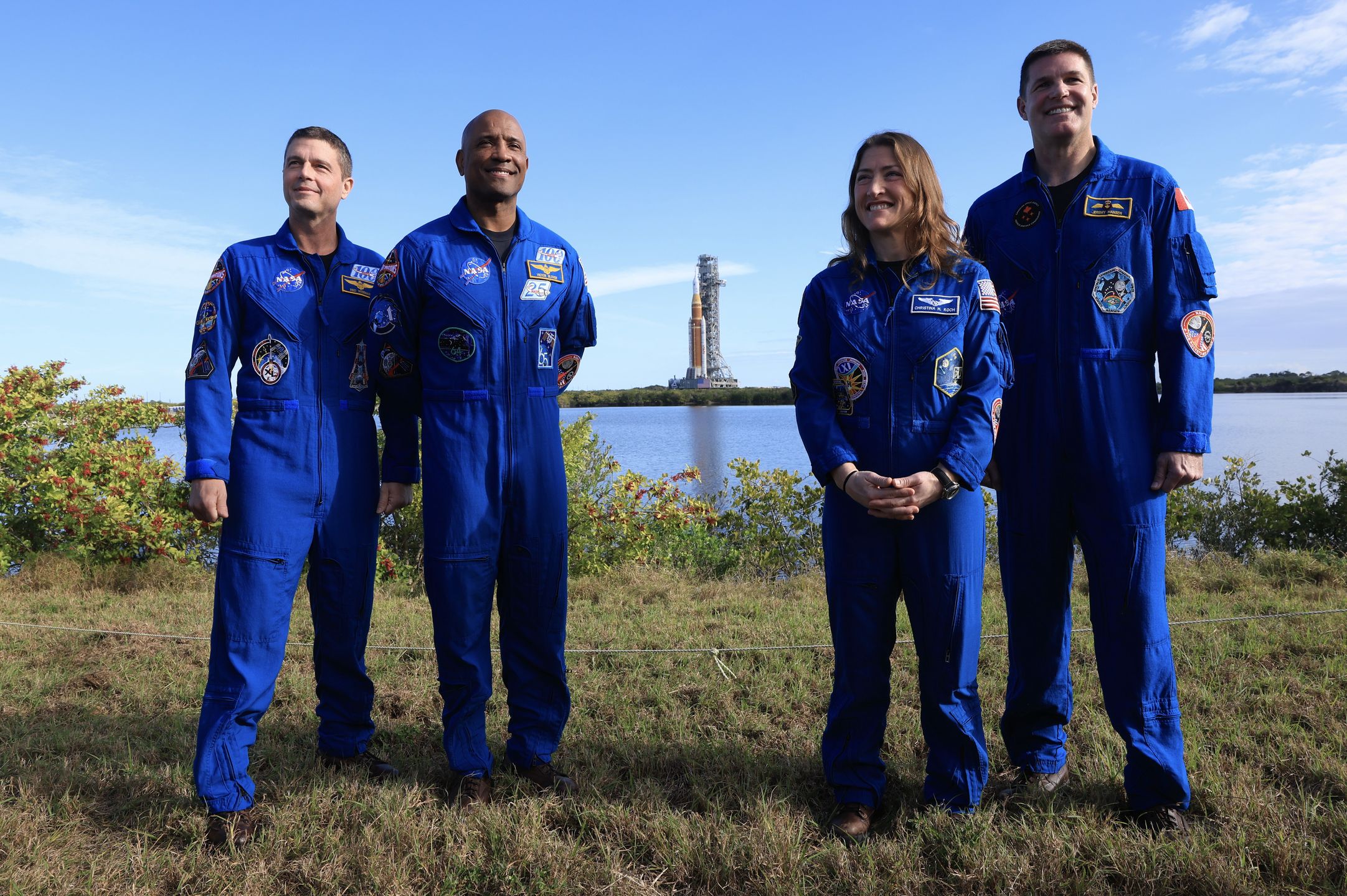 CAPE CANAVERAL, FLORIDA - JANUARY 17:  (L-R) NASA's Artemis II Commander Reid Wiseman, pilot Victor Glover, mission specialist Christina Koch, and Jeremy Hansen pose for a photo as NASA's Artemis II (behind them) is rolled from the Vehicle Assembly Building to Launch Pad 39B at NASA’s Kennedy Space Center on January 17, 2026 in Cape Canaveral, Florida. NASA’s integrated SLS (Space Launch System) rocket and Orion spacecraft for the Artemis II mission are being rolled to Launch Pad 39B ahead of the 10-day mission in February 2026, which will take the crew around the Moon and back to Earth.  (Photo by Joe Raedle/Getty Images)