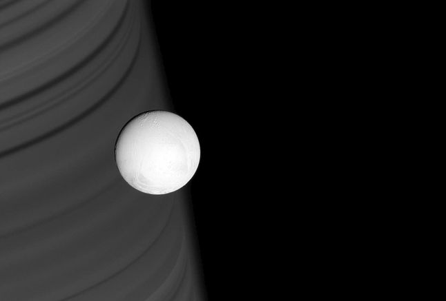 Pierścienie Saturna tworzą malownicze tło dla zamarzniętego księżyca – Enceladusa. Zdjęcie powstało 28 czerwca 2007 roku.