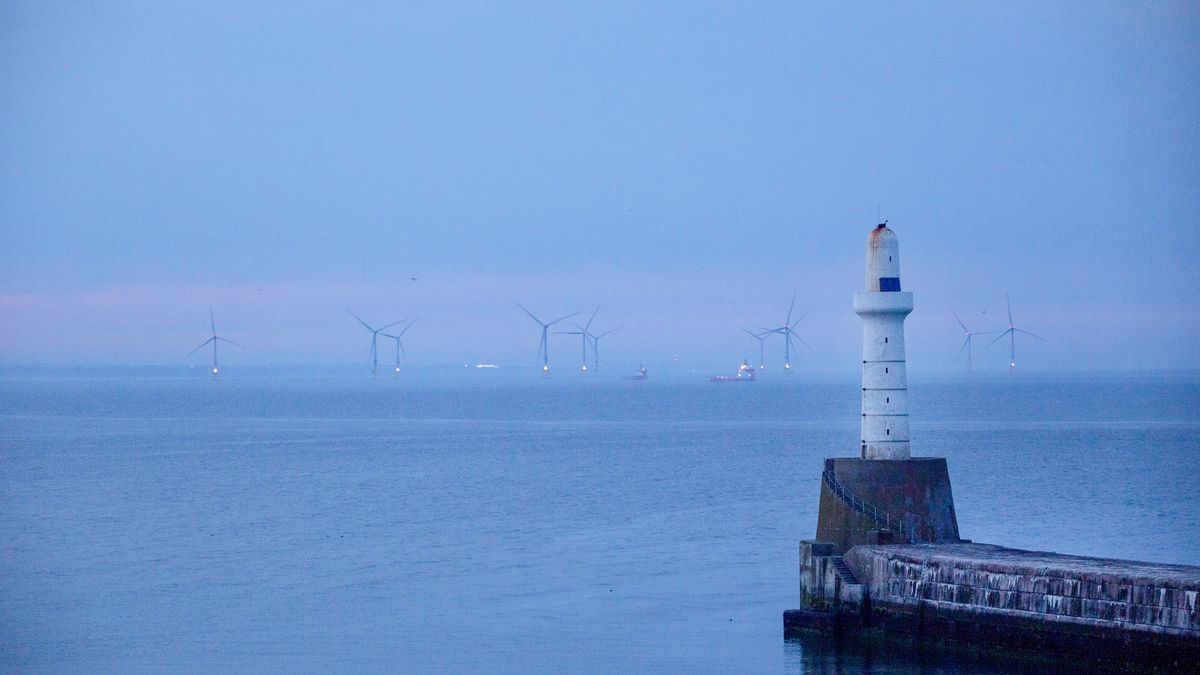 Offshore wind turbines beyond the harbour arm at the Port of Aberdeen sea port at dusk in Aberdeen, UK, on Monday, July 18, 2022. Aberdeen in northeast Scotland is trying to make the leap from an oil town to a renewables hub amid growing demand for cheap home-grown energy. Photographer: Emily Macinnes/Bloomberg via Getty Images