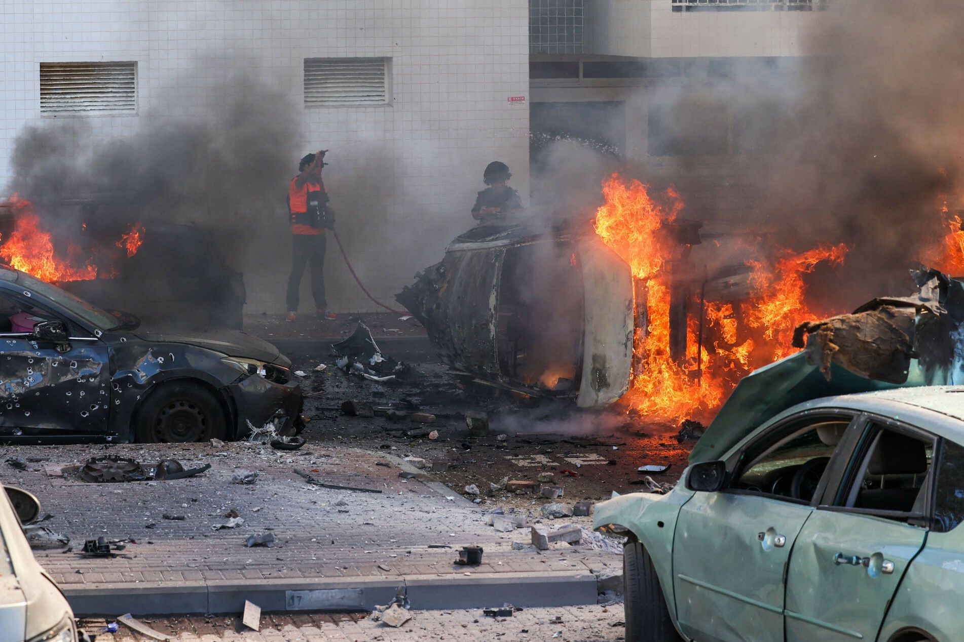 Atak rakietowy ze Strefy GazyPeople try to extinguish fire on cars following a rocket attack from the Gaza Strip in Ashkelon, southern Israel, on October 7, 2023. Palestinian militant group Hamas has launched a "war" against Israel, Defence Minister Yoav Gallant said, after barrages of rockets were fired from the Gaza Strip into Israeli territory on October 7. (Photo by AHMAD GHARABLI / AFP)AHMAD GHARABLI