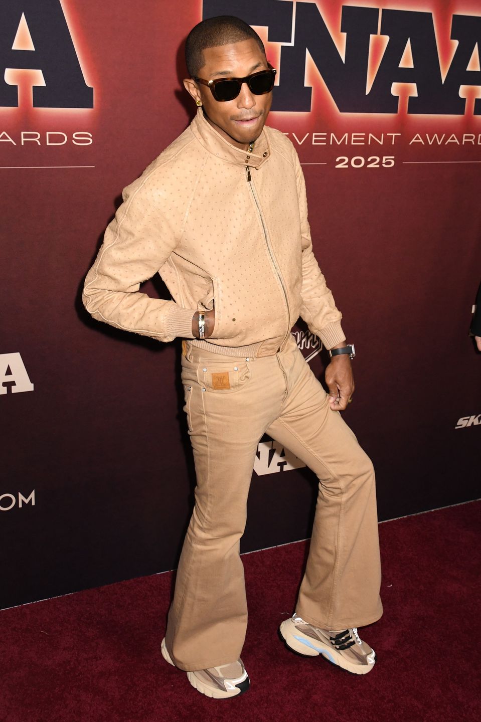 Pharrell Williams oślepia złotym uśmiechem na ściance