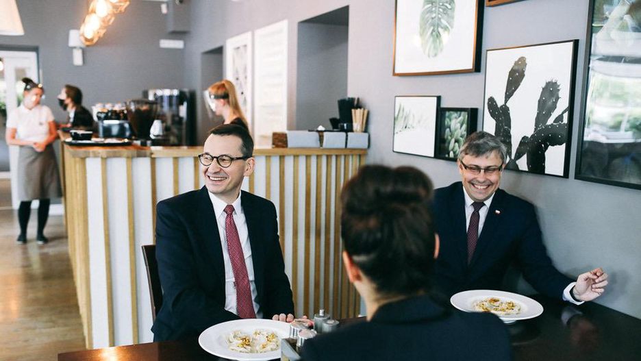 Premier w restauracji, z obcymi osobami przy jednym stoliku.