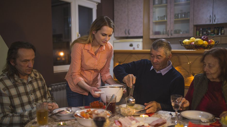 Young woman serving food during family dinner at home
Young woman serving homemade food during family dinner with parents and grandparents at home
cream_ph