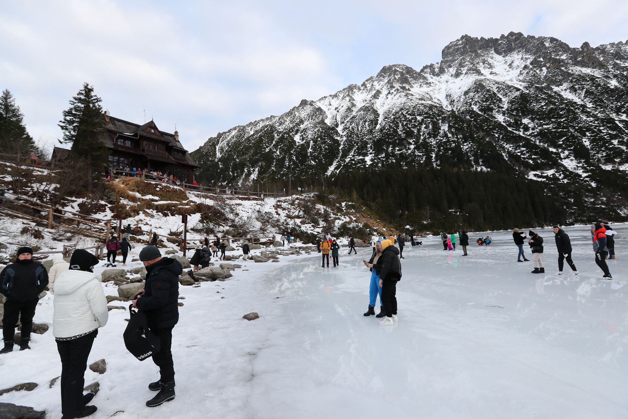 Tatry, Morskie Oko, 26.12.2022. Turyści na tafli lodu na jeziorze Morskie Oko w Tatrach, 26 bm. Tatrzański Park Narodowy ostrzega przed wchodzeniem na zamarznięte górskie jeziora � z powodu panujących w ciągu dnia dodatnich temperatur lód jest bardzo cienki i grozi załamaniem. (jm) PAP/Grzegorz Momot