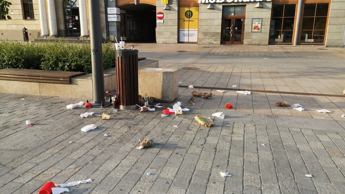 Porozrzucane śmieci przy koszu na placu Litewskim