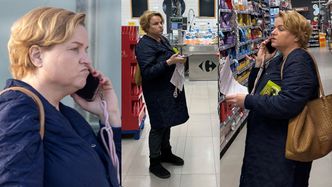 Zamyślona Katarzyna Bosacka buszuje po supermarkecie z telefonem przy uchu i z plikiem kartek w rękach