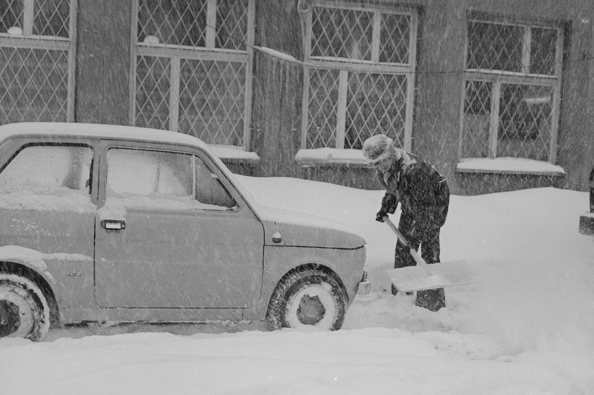 Mężczyzna odśnieża auto