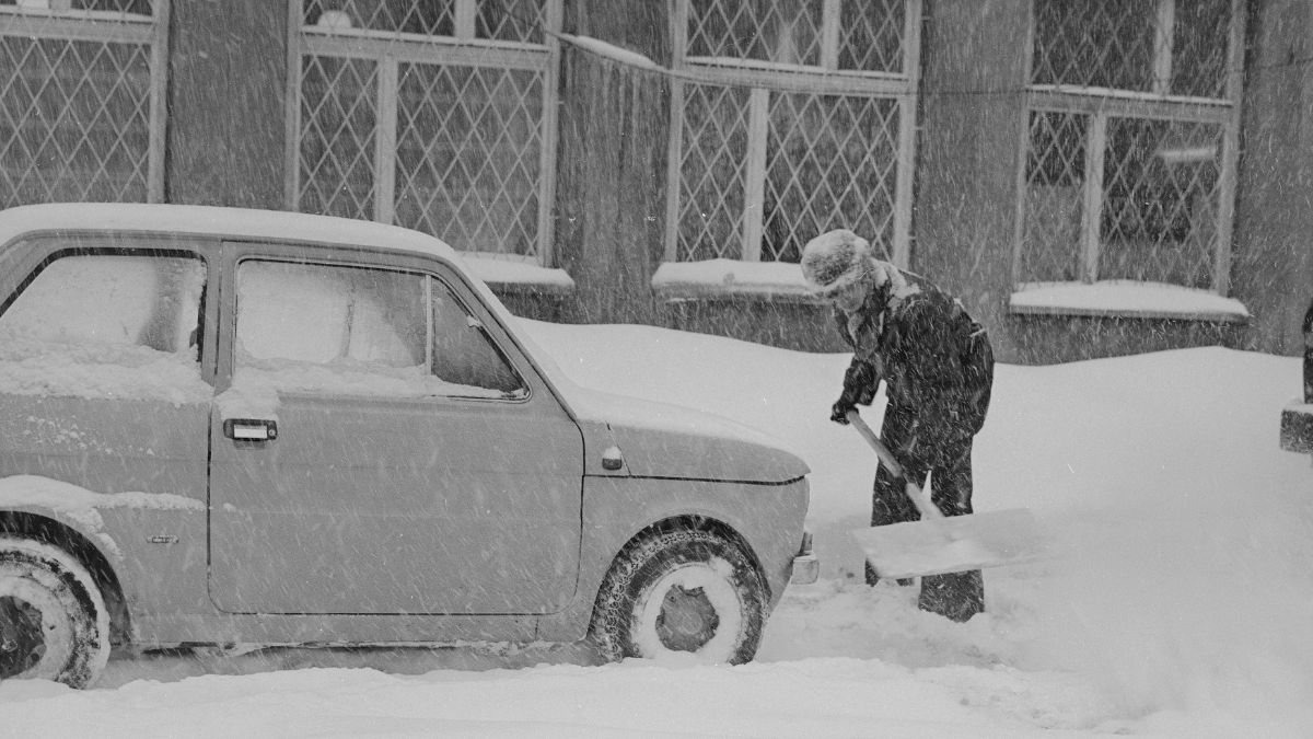 Mężczyzna odśnieża auto