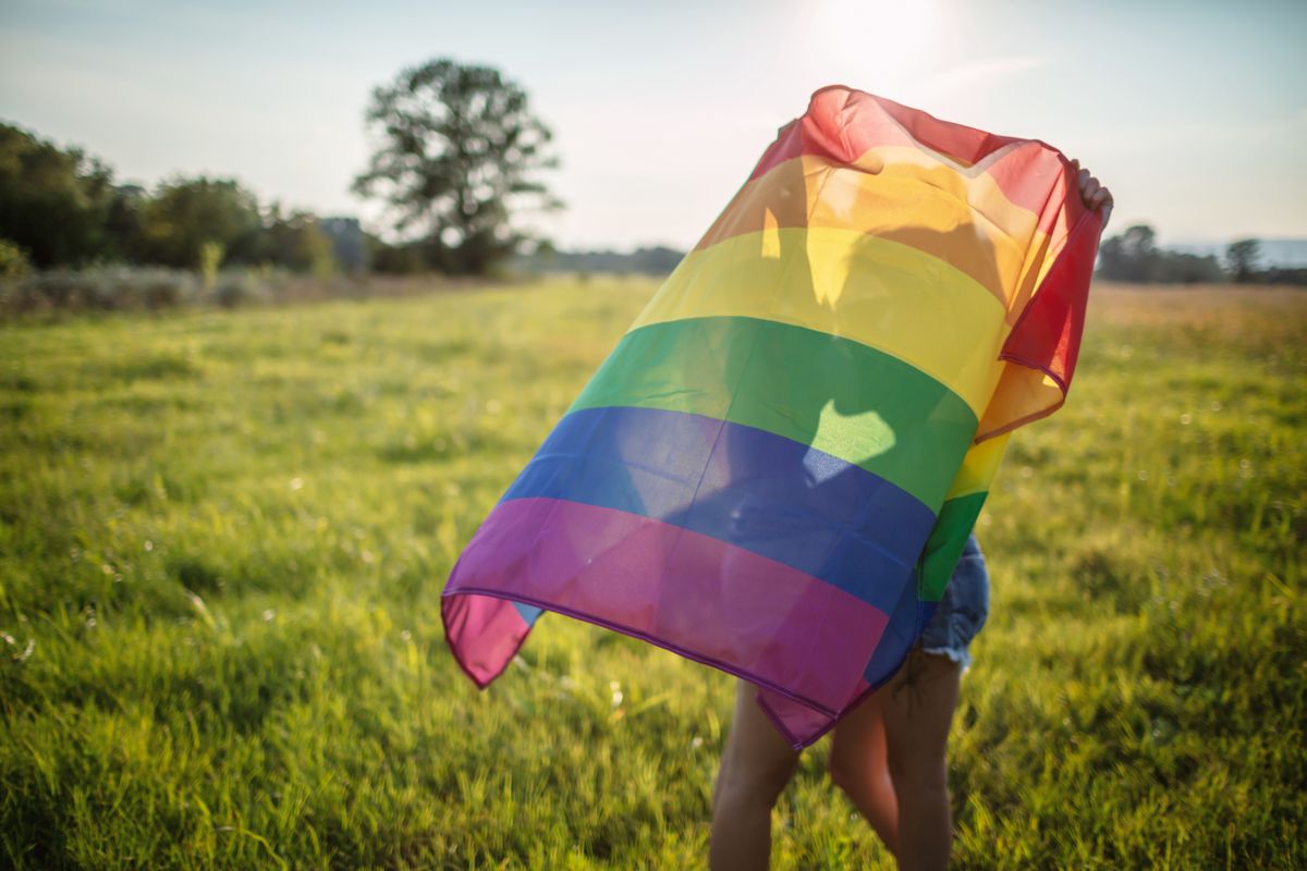 Lesbian women kissing behind the rainbow flag