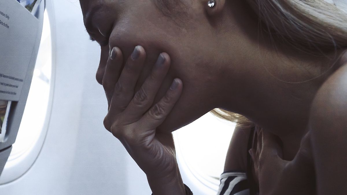 Woman feeling sick and puking in AirplaneThe fear in the plane. The frightened woman has a fear of flying airplane. A passenger traveling on the affected aircraft. Asian tourists with the stress on the flying air plane.Enes Evren