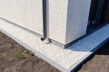 Białe kamyki wokół domu. Ozdoba czy genialna tarcza na deszcz?