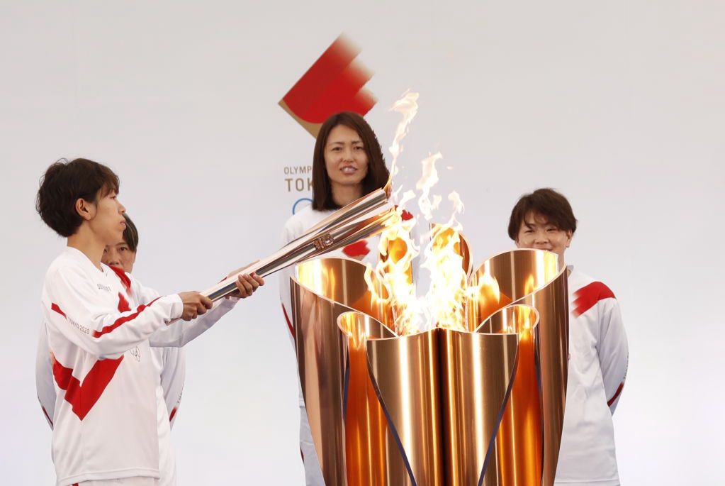 Azusa Iwashimizu, członkini reprezentacji Japonii w piłce nożnej kobiet, zapala pochodnię z uroczystego kotła z ogniem olimpijskim